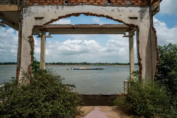 A barge loaded with freshly dredged sand passes by an abandoned house on the Tien River, as the northern branch of the Mekong is called in Vietnam. Along with sand mining, climate change and the building of dams threaten fishing and other uses of the river. Image by Sim Chi Yin. Vietnam, 2017.