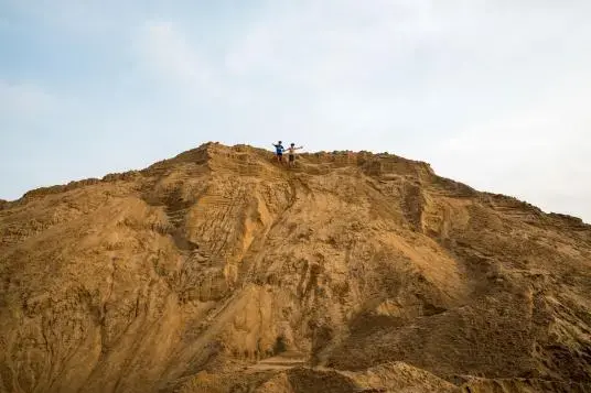 Nguyen Gia Lac, 10, and Nguyen Trung Kien, 12, play on a giant sand pile by their village on Chau Ma island in Dong Thap Province, near the Cambodian border. The stockpile of sand from the nearby Tien River occupies what used to be farmland and belongs to a businessman from elsewhere in Vietnam. While sand mining is unpopular among villagers for the noise and erosion it causes, the sand mountain is a local attraction. Image by Sim Chi Yin. Vietnam, 2017.