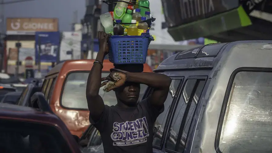 Dense traffic, too, contributes to the problem. Here, cars move so slowly that street vendors walk between them to peddle their wares. Image by Larry C. Price. Nigeria, 2018.