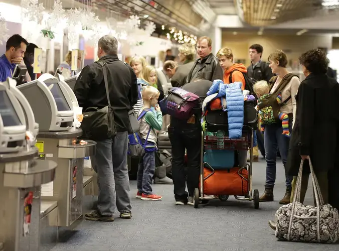 Ticket agents work with travelers in the Southwest ticketing area at Mitchell International Airport in 2015. Passengers, unwilling to postpone plans, sometimes travel while sick. Passengers can also harbor a virus without showing symptoms, meaning that they aren't even aware that they could be passing a disease to fellow passengers. Image by Mike de Sisti/Milwaukee Journal Sentinel. United States, 2015.