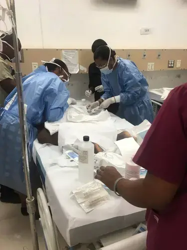 Dr. Pascale Yola Gassant, far right, performs a test on Djooly Jeune, 18, while staff members at the University Hospital of Mirebalais in central Haiti observe. Gassant, a pediatric oncologist, founded Haiti’s only childhood cancer program at St. Damien Pediatric Hospital in metropolitan Port-au-Prince. Image courtesy of Dr. Maxi Raymonville. Haiti, 2018.