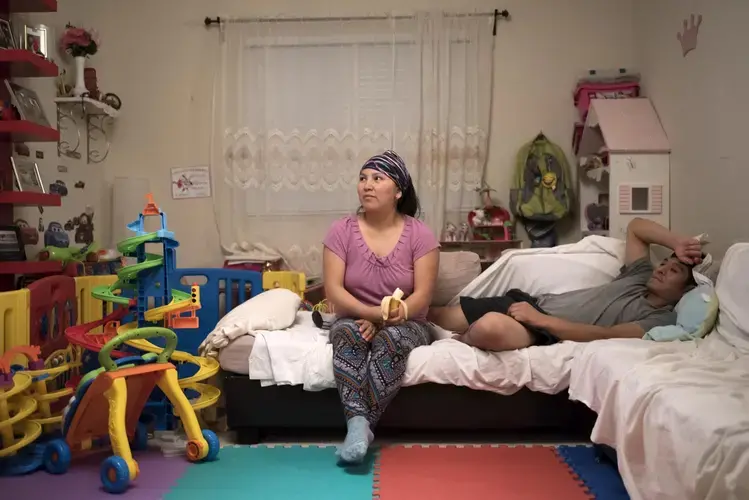 Erika Yave and Alvaro Jordan rest on their couch in Annandale, Virginia, after Alvaro comes back from working while Erika has been taking care of their two children. Image by Carey Averbook. United States, 2016.