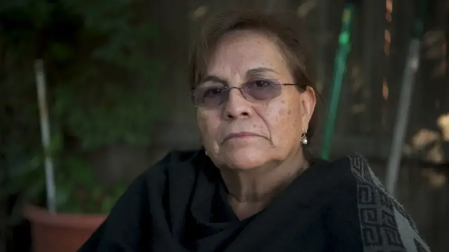 Julia García sits for a video portrait underneath the peach tree in her backyard. She brought the seed for the peach tree from Bolivia and sitting here reminds her of being at her home there. She says, “It transports me to Bolivia.” Image by Carey Averbook. United States, 2016.