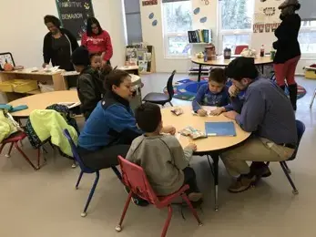 During the Afterschool Homework session. Egan was helping a student, while a parent was studying with her son. Image by Thea Gu. United States, 2017.