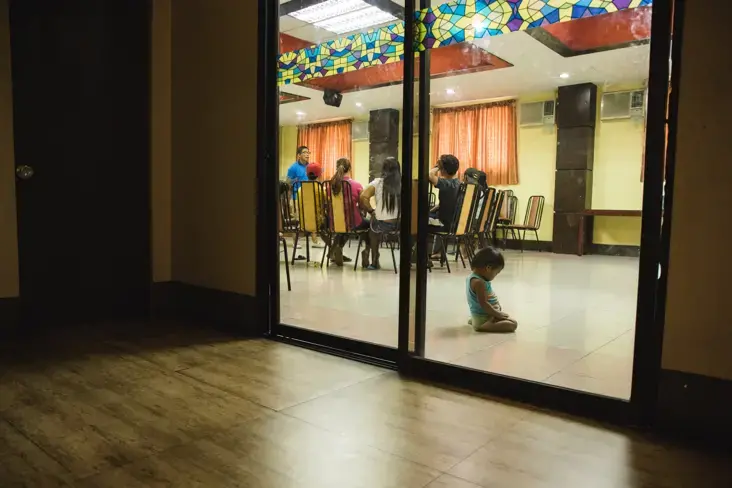 A child waits while families of slain drug suspects listen to a discussion, facilitated by Rise Up for Life and for Rights, about the mental health system in the Philippines. Image by Pat Nabong. Philippines, 2017.