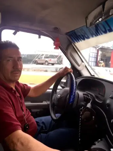 José Luís Cisneros Dávila at the wheel of his taxi de ruta, a converted ambulance. Image by Patrick Reilly. Mexico, 2017.<br />
