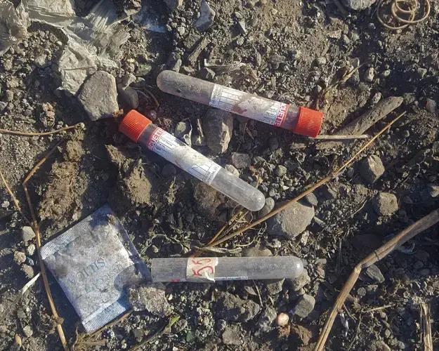 Medical waste, including these vials from blood tests, is dumped alongside other trash at the Truitter dump. The new general hospital building, now under construction, will include an incinerator for that waste. Image by Rebecca Hersher. Haiti, 2017.