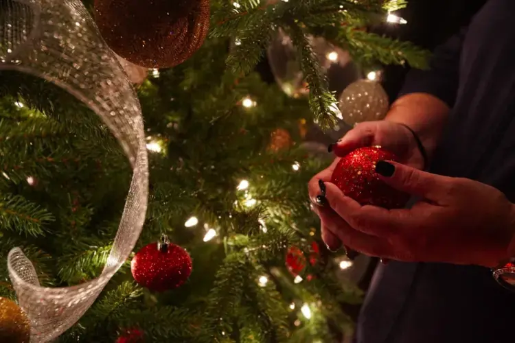 A Memphis victim of domestic violence handles a fragile Christmas ornament at a Mid-South shelter. Image by Karen Pulfer Focht/Special to Daili Memphian. United States, 2020.