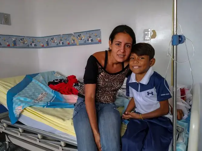 Emily Aguiar and her 12-year-old son, Eliécer Aguiar, at the Hospital J.M de los Ríos in Caracas, where Eliécer remains hospitalized due to an infection in one of the stiches around his dialysis catheter. Eliécer suffers from severe kidney decease and needs a kidney transplant to survive. Image by Flaviana Sandoval. Venezuela, 2018.