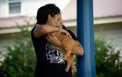 Tianna Sugars, 22, hugs her cat Tito on the front porch of her South Paris home. Sugars spoke about seeing the effects of her mother’s employment at home. Image by Linda Coan O’Kresik/BDN. United States.<br />