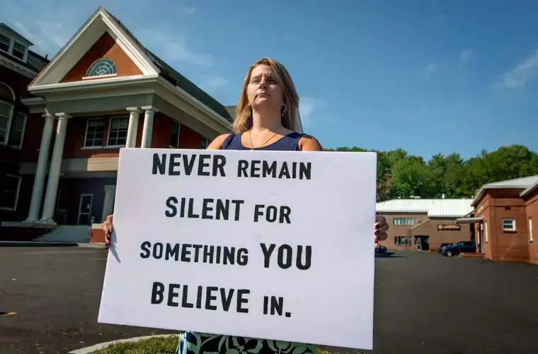 Christina Sugars holds a sign as a message to others to not keep quiet about things that matter to them. Sugars said she cannot fully share her feelings and thoughts about her time as a school resource officer with the Oxford County Sheriff’s Office. Image by Linda Coan O’Kresik/BDN. United States.<br />
