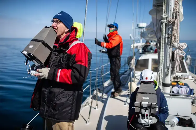 Michael Moore (left) and Carolyn Miller worked to collect whale data on Moore’s sailboat Rosita in Cape Cod Bay. Image by Aram Boghosian/The Boston Globe. United States, 2019.