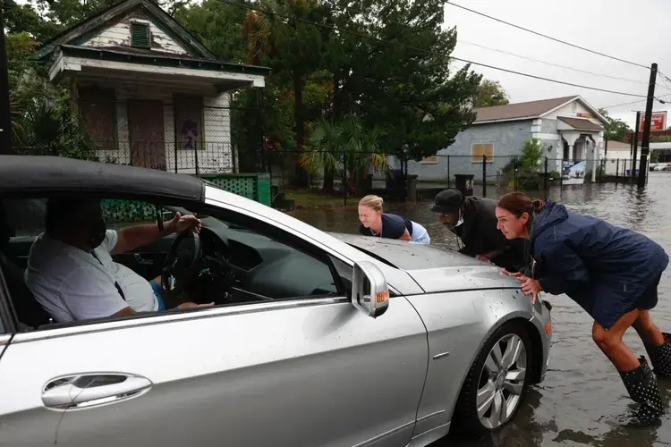 Gary Harris (left) gets help from Nathaniel Seabrook and two faculty members from Sacred Heart Catholic school. Rain flooded downtown Charleston on Friday, Sept. 25, 2020. Andrew J. Whitaker/Post and Courier Staff. United States, 2020.