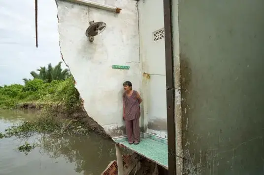 In July 2017, Ba Tu, 72, returned to what's left of her house in Nha Be, a suburb of Ho Chi Minh City. Four days earlier, part of the house had fallen into the river. Ba Tu was home with her daughter-in-law when it happened, but both women escaped injury. Image by Sim Chi Yin. Vietnam, 2017.