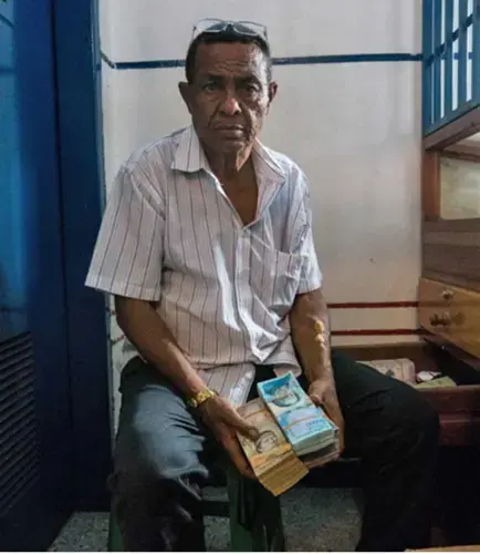 The owner of a local gold pawn shop in Tumeremo, Bolivar state, shows a stack of Venezuelan money, worth only a few dollars due to the nation’s rapidly escalating inflation. Image by Bram Ebus. Venezuela, 2017.