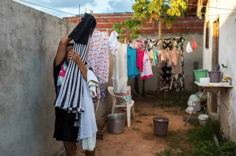 Cecilia takes down the laundry at the home she shares with Maria Clara. Image by Lianne Milton. Brazil, 2018.