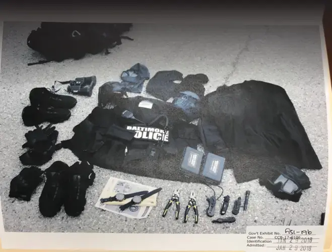 Federal prosecutors displayed the contents of a bag found in the trunk of Sgt. Wayne Jenkins' police vehicle when he was arrested in 2017. The bag contained masks and other gear he used while stealing drugs and cash from people he and his team targeted. Baltimore, Maryland. 2017, Image by U.S. Attorney's Office.