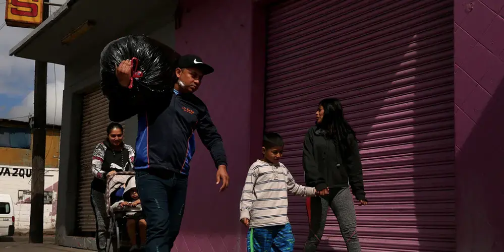 Aracely, Juan Carlos, their children and a friend walk to a laundromat in Tijuana. Hugo Castro, of the nonprofit Border Angels, says his organization works with the shelter they lived in and eight others around Tijuana, providing volunteers, donated goods and medical assistance. Castro said migrants and asylum-seekers are fleeing violence, extortion and deaths of family members. “They are in survival mode and just want to stay alive,” he says. Image by Erika Schultz. Mexico, 2019.