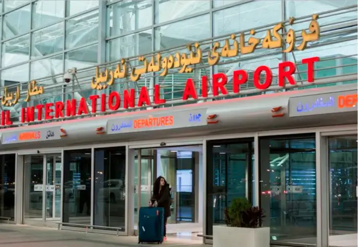 With a four-foot, two-pronged, gold sword in her suitcase, Zahra Ahmad walks toward security at Erbil International Airport in Erbil, Iraqi-Kurdistan on Saturday, Feb. 16, 2019. Ahmad received the sword when she visited her family for the first time in Baghdad. The sword is called Zulfiqar or Imam Ali ibn Abi Talib's sword. The sword made it through the airports of Baghdad, Erbil, Turkey, Amsterdam, Iceland and Detroit. Image by Brontë Wittpenn. Iraq, 2019.