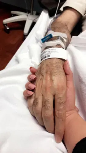 Zahra Ahmad holds Mohammad Sibte's, her father, hand at Beaumont Hospital in Dearborn, Michigan. Image by Zahra Ahmad. United States, 2019.