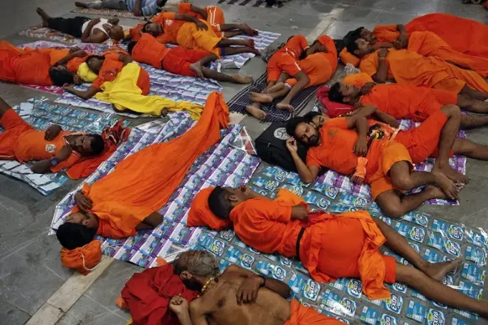 Kanwarias, worshippers of the Hindu god Shiva, sleep as they wait for their train before a ritual pilgrimage at a railway station in Allahabad, India, on July 29, 2018. Image by Rajesh Kumar Singh / AP. India, 2018.