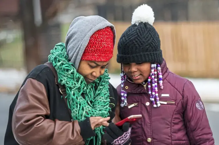 Nicole Glaze, owner of Great Start Day Care, and Kee’Miyah look at Kee'Miyah's Christmas toy wishlist. Image by Michael M. Santiago/Post-Gazette. United States, 2019.