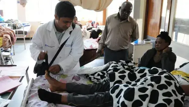 Dr. Omar Siddiqi attends to a patient in a ward at University Teaching Hospital in Lusaka. Image courtesy of Quartz. Zambia, 2019.
