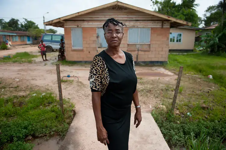 Gladys Renfurm stands for a portrait above pooled water tainted with sewage in her neighborhood in Moengo, Suriname. “You can smell it,” said Renfurm, an elementary school teacher who lives on the block most affected by the sewer overflows. “Yesterday the whole street was entirely under water. It flowed like a river,” she said. “If it has rained, you can’t breathe.” Image by Stephanie Strasburg. Suriname, 2017.