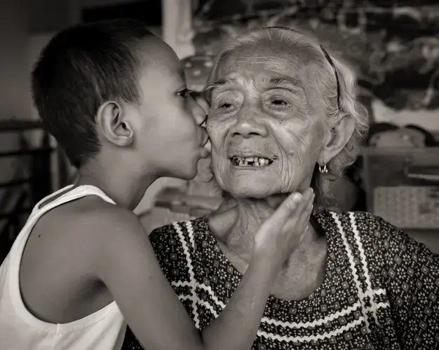 Narcisa Claveria receives a gentle kiss from her great-grandson, Joseph Tena, 8, whom she and her husband have raised since his father died when he was an infant. Claveria was 12 when Japanese soldiers took her as a sex slave for 1 1/2 years. They raped her mother and skinned her father alive before burning down their house. She could hear him scream, 'Children, where are you? I'm in such pain.' Image by Cheryl Diaz Meyer. Philippines, 2019.