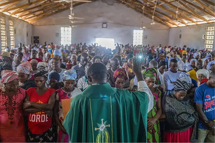 In Aliade, Nigeria’s St. Vincent de Paul Church, Reverend Emmanuel Dagi blesses pregnant parishioners and encourages them to attend the Baby Shower program. Image by Misha Friedman. Nigeria, 2018.
