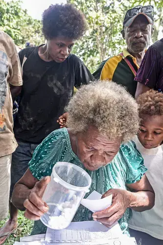 The new eradication effort is based on mass drug administration. Volunteers dole out antibiotic tablets to everyone, regardless of whether they show symptoms. Image by Brian Cassey. Papua New Guinea, 2018. 