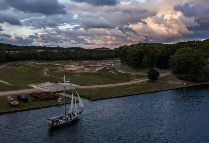 A sailboat passes by a new development on the site of Singapore, a former town at Lake Michigan on the Kalamazoo River near Saugatuck, Michigan, on Sept. 29, 2020. Image by Zbigniew Bzdak/Chicago Tribune. United States, 2020.