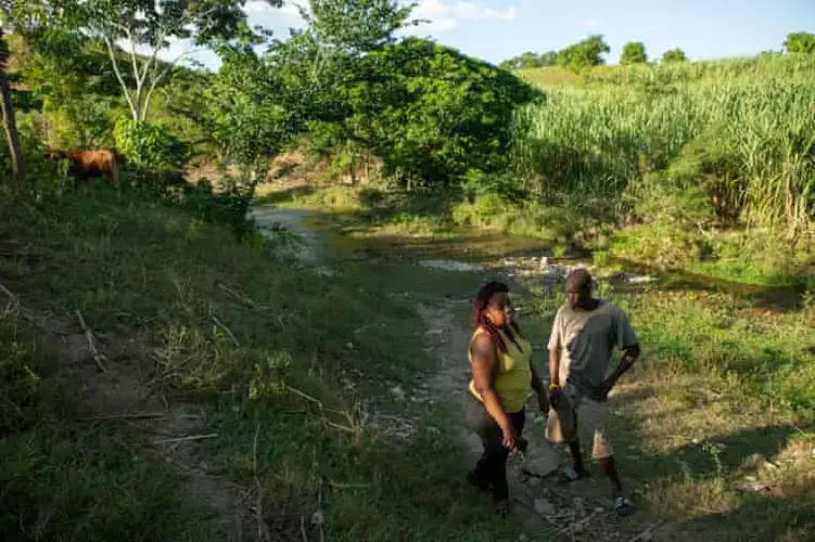 Marie Millande Tulmé, an epidemiologist, speaks with Reynald Louis Charles, a farmer, by the Meille River at the former UN base near Mirebalais. Image by Allison Shelley. Haiti, 2020.