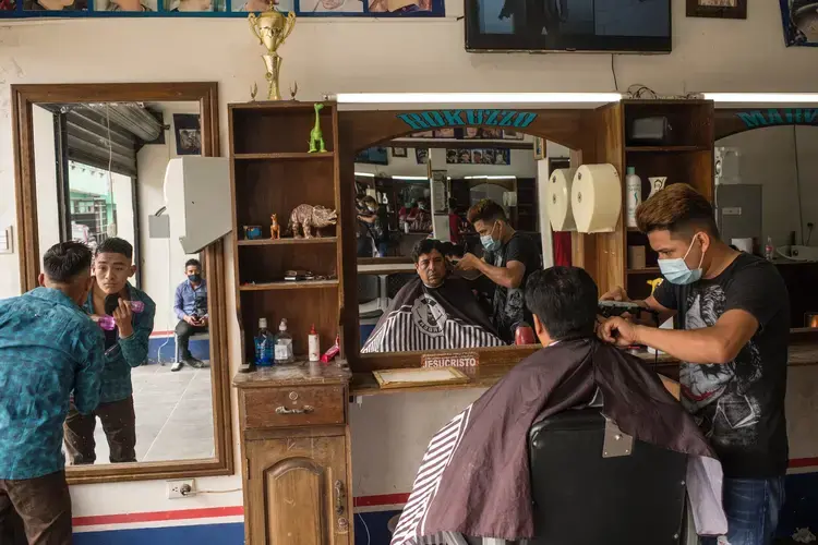 Roberto’s brother, Marvin, at Rokuzzo, the barbershop founded by Roberto in Cubulco. Roberto left the business to his younger brothers before he began his journey to the United States. Image by Daniele Volpe/The New York Times. Guatemala, undated.<br />
