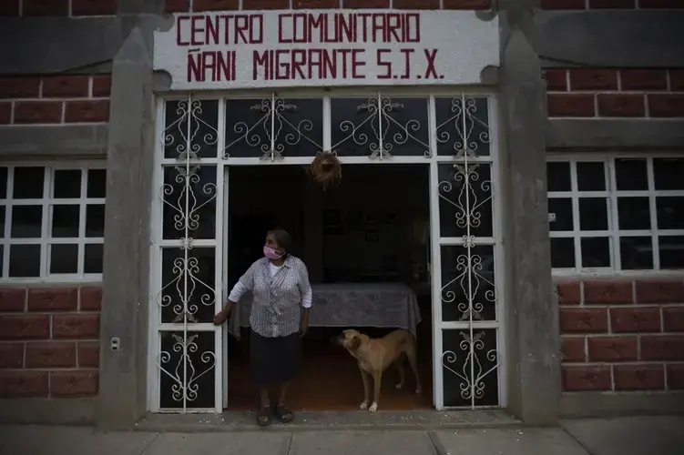 Clara Lara, whose son lives in Staten Island, New York, stands outside the home that her son built for himself and in the meantime serves as a community center while he's away, in San Jeronimo Xayacatlan, Mexico, Thursday, June 25, 2020. Image by Fernando Llano/AP Photo. Mexico, 2020.