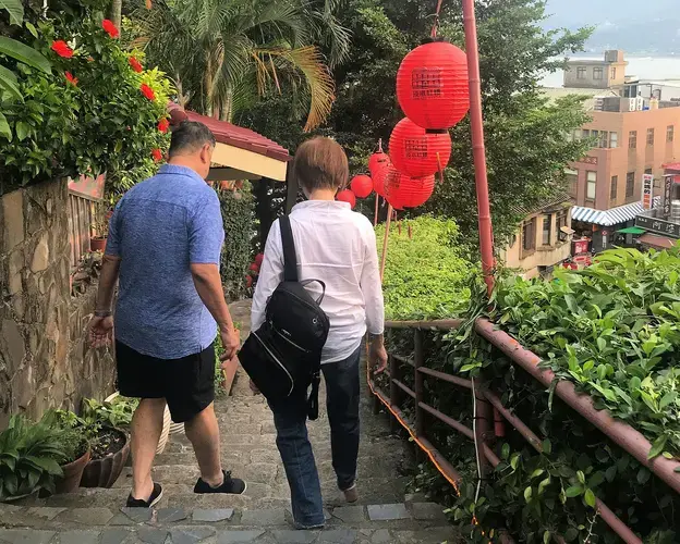 Mike and Grace Chen walk down city steps in Tamsui in New Taipei City. Image by Melissa McCart. Taiwan, 2018.