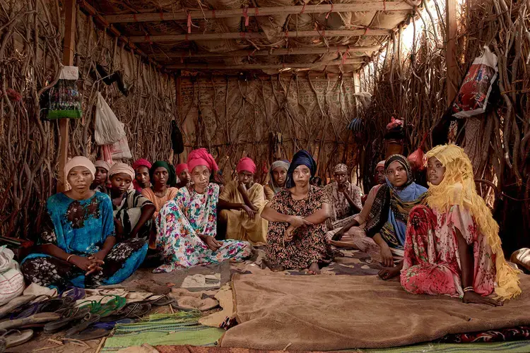 In this July 25, 2019 photo, Ethiopian migrant girls sit inside in a lockup known in Arabic as a 'hosh,' in Ras al-Ara, Lahj, Yemen. Some lockups hold as many as 50 women at a time. The women will stay here for several days until their transportation is ready. Image by Nariman El-Mofty / AP Photo. Yemen, 2019.