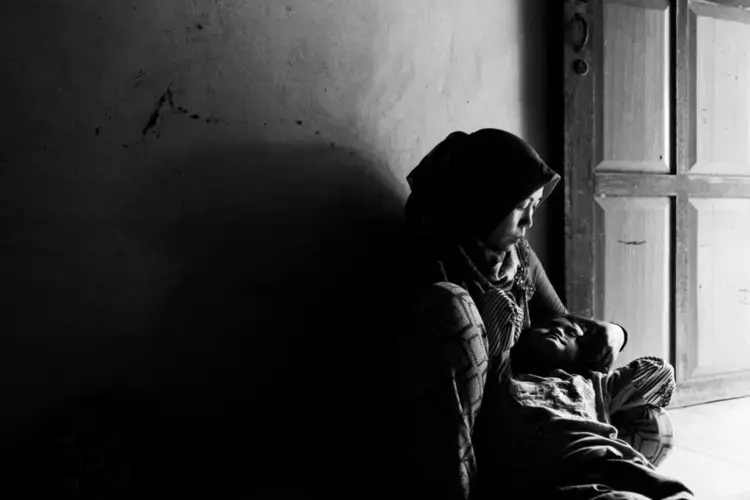 Asnia shares a tender moment with her daughter Dewi after work. Dewi is deaf and mute. Asnia works in a palm oil plantation in Riau, Indonesia to save money for her daughters treatment. June 27, 2018. Image by Xyza Cruz Bacani. Indonesia, 2018.