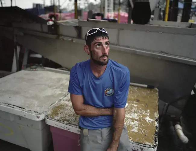 Dulac. Chance McCorkel, Kim and David Chauvin’s nephew, takes a break to shelter from the rain while unloading shrimp. Image by Spike Johnson. United States, 2019.