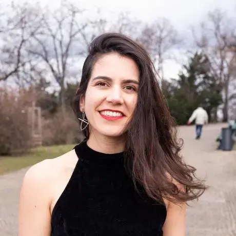 A person with a black crop top smiles at the camera.