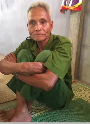 A man in green sits on the floor.