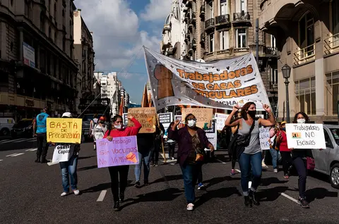 People walk down a street during a protest. They are holding signs.