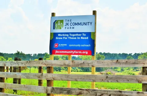 A sign for The JK Community Farm with the phrase, "Working Together to Grow for Those in Need".
