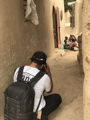 Gavin McIntyre crouches down to take a photograph in a narrow street.