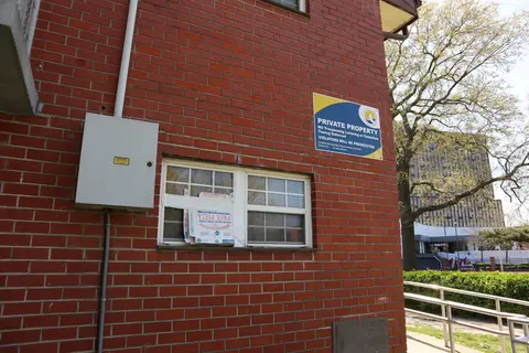 Someone has used a pizza box to fix a broken window of a red brick building.