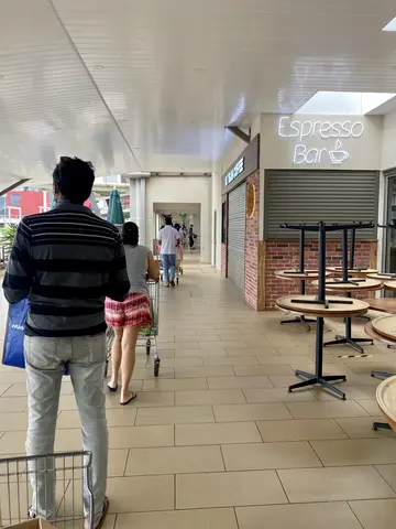 People stand, socially distanced, in line with shopping carts.