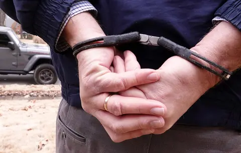 A man is shown handcuffed.