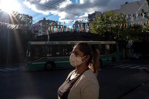 A person wearing a cloth medical face mask. There is a bus in the background.