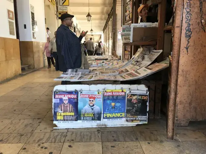 A customer talks to the vendor of a newsstand in Morocco's capital. Very few publications in Morocco offer critical reporting of the government or the royal family, which uses a system of economic oppression to control what is published. Image by Jackie Spinner. Morocco, 2017.