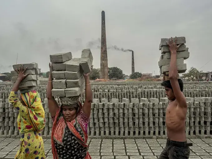 Workers carry bricks after they are formed and stack them in preparation for firing. Roughly one million people are employed in Bangladesh's brickmaking facilities, which generate nearly 60 percent of the particulate pollution in Dhaka. Image by Larry C. Price. Bangladesh, 2018.
